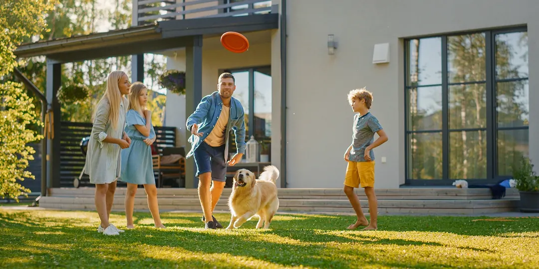 A family playing with their dog outside their new home