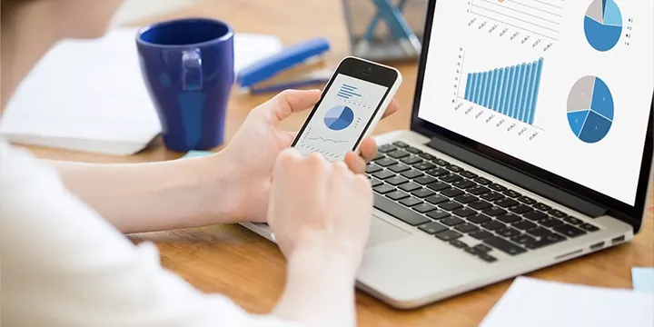 Someone checking their finances on a laptop and phone